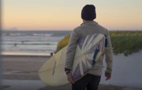 男子手拿冲浪板走向海边背影视频素材