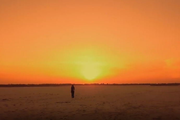 晚霞中走在平原的女子短视频素材
