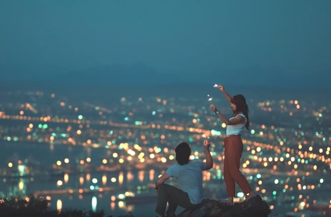 情侣在山顶游玩，山下灯火辉煌