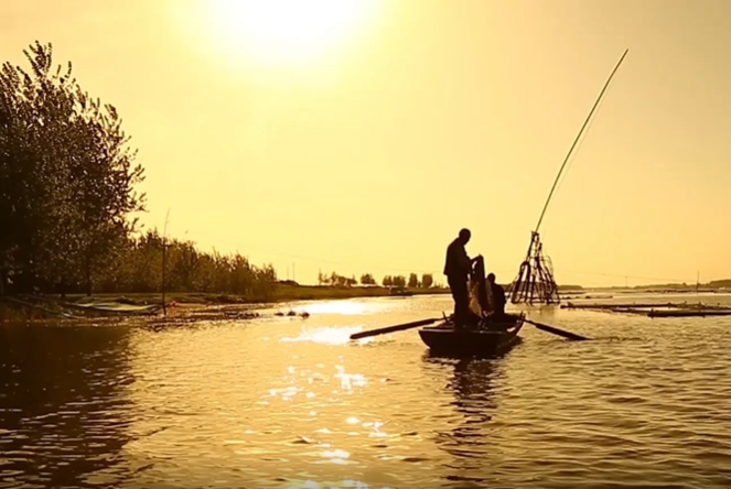 夕阳的在湖中打渔的人民