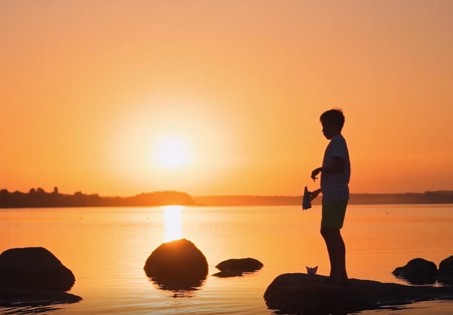 夕阳边的池塘边小男孩玩飞机视频素材