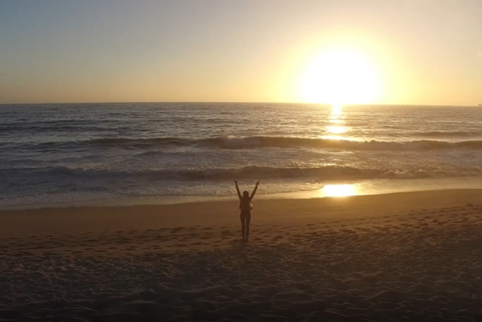 夕阳海边的女孩迎风挥手