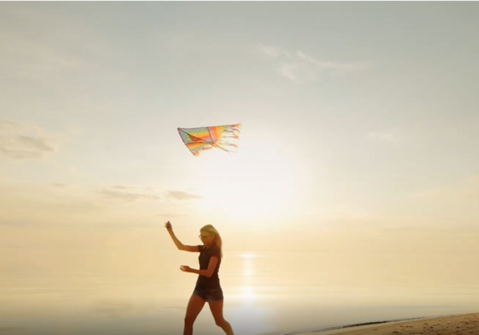 日落海边沙滩放风筝的女孩子