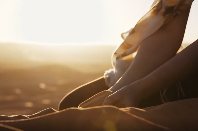 日落下的女孩子在沙滩玩沙子