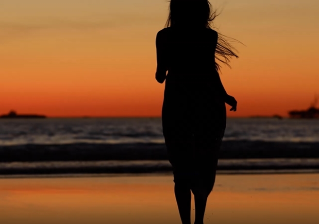 日落下海边女孩子在沙滩边跑步视频素材