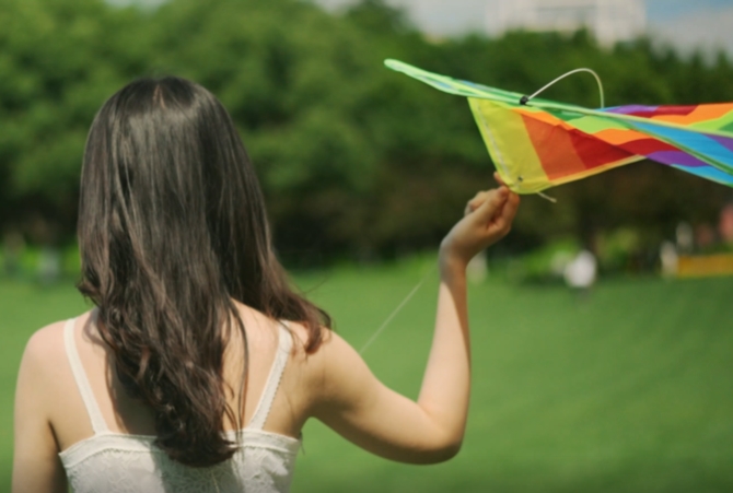 公园草地上放风筝女孩的背影