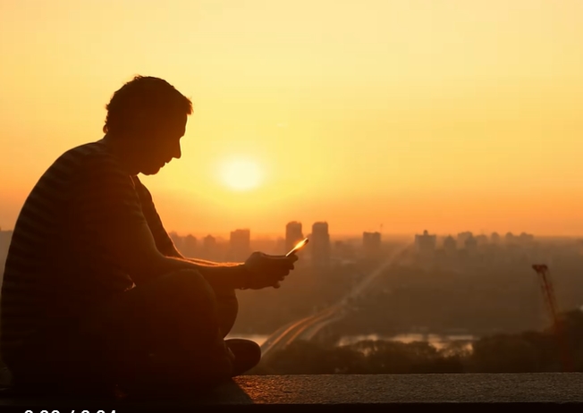 男子夕阳下手机发信息侧影视频素材